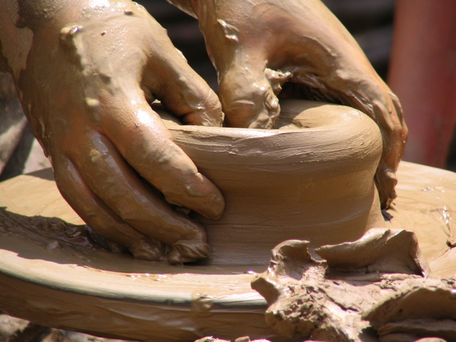 Hands shaping clay on a potter's wheel